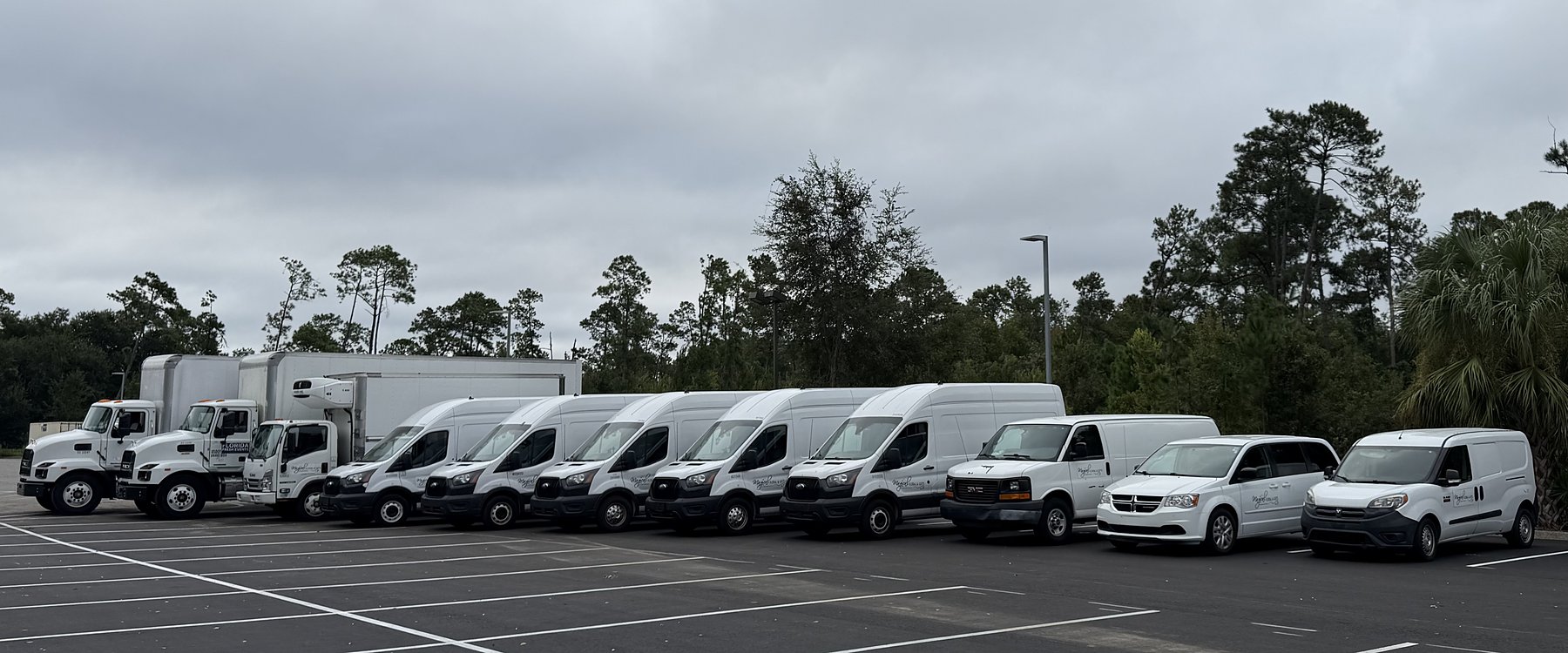 The Florida Fresh Events delivery fleet lined up at our yard — box trucks, a refrigerated truck, and cargo vans