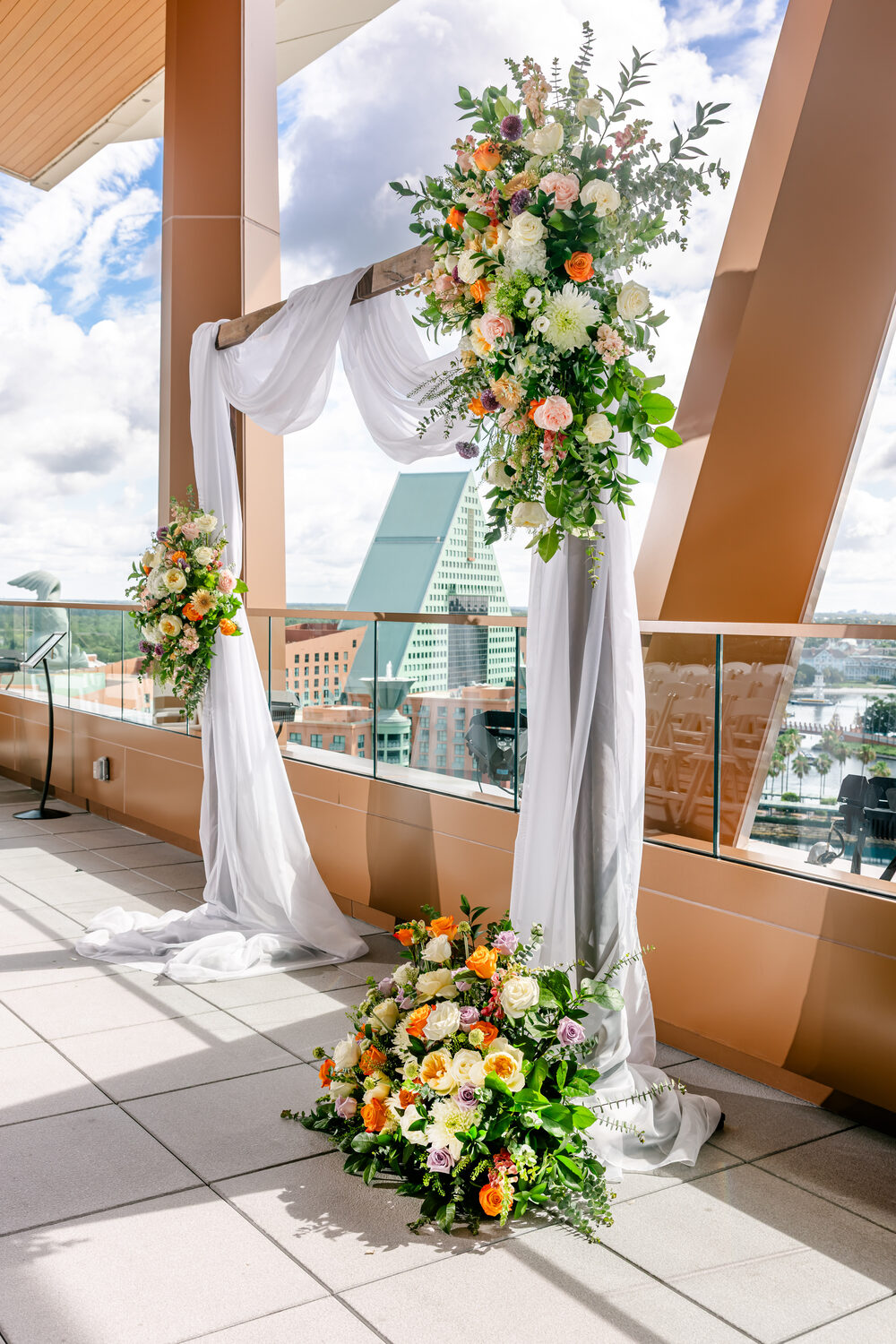 Rooftop ceremony arch with lush florals and draping