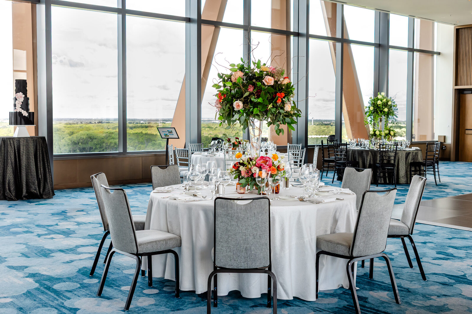 Ballroom reception with round tables and tall floral centerpieces