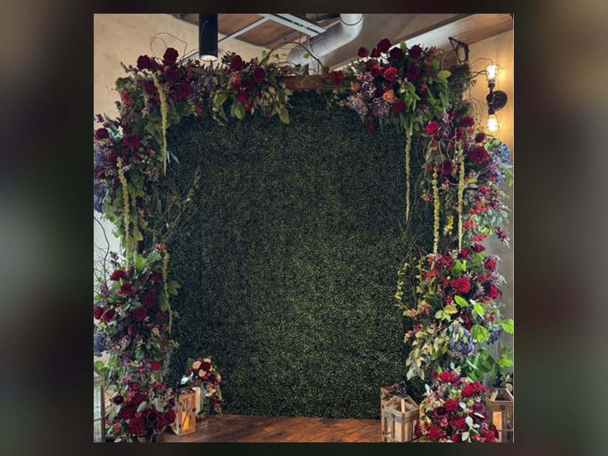 Boxwood hedge wall dressed with holiday florals and gifts